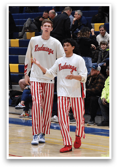 Three basketball players wearing red and white striped pants are walking on a basketball court. AI generated content