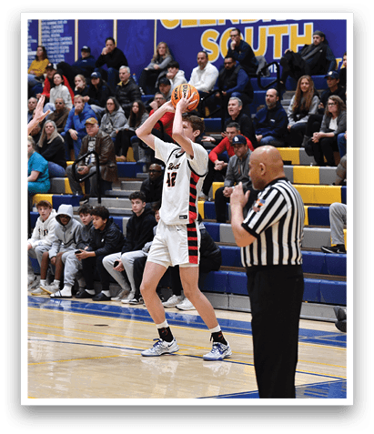 A basketball game is taking place with a player in the air attempting to shoot the ball. The referee is watching closely as the players compete. AI generated content