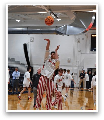 A group of people playing basketball in a gym. One player is attempting to block a shot. AI generated content
