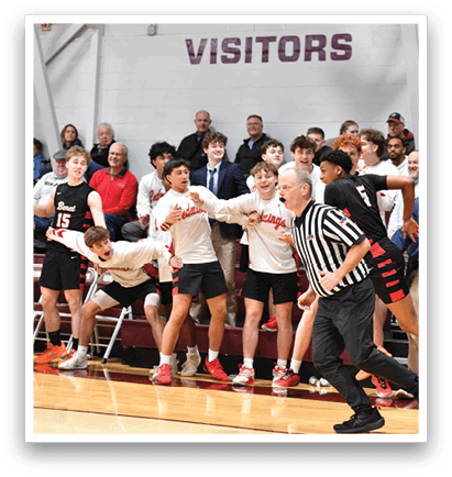 A group of people are playing basketball, with a referee standing in the middle of the court. The players are wearing red and white uniforms, and the referee is wearing a black suit. The crowd is watching the game from the stands. AI generated content