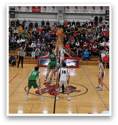 A basketball game is taking place with a crowd of people watching. The players are wearing uniforms and the game is in progress. The audience is seated on chairs surrounding the court. AI generated content