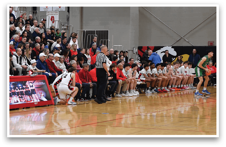 A basketball game is taking place with a crowd of people watching. The players are on the court, and there are several chairs placed around the area. A man is holding a basketball, and a woman is holding a clipboard. The scene is lively and filled with excitement. AI generated content