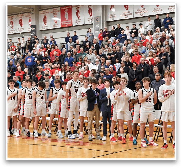 A group of young men stand on a basketball court, some wearing suits and ties. They are lined up in front of a crowd, possibly for a ceremony or event. AI generated content