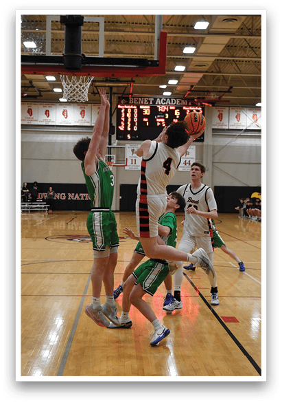 A basketball game is taking place in a gymnasium with two teams playing. One player is attempting to block a shot, while another player is reaching for the ball. The gym is filled with spectators, and the atmosphere is intense. AI generated content