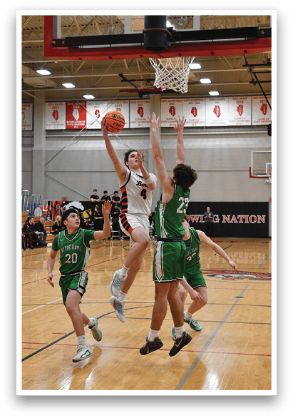 A basketball game is taking place with two teams playing against each other. One player is jumping up to block a shot, while another player is attempting to score. The game is being watched by a crowd of people. AI generated content