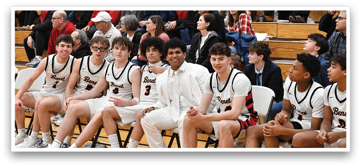 A group of young men are sitting on chairs in a gym, wearing uniforms. They are waiting for their turn to play in a basketball game. AI generated content