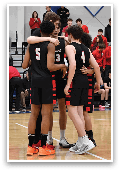 A group of people are standing on a basketball court, some of them wearing black uniforms. They are huddled together, possibly discussing their game strategy or sharing encouragement. The crowd of spectators is watching the game from the sidelines, with some of them sitting on chairs. The atmosphere appears to be competitive and focused, as the players prepare for the next play. AI generated content