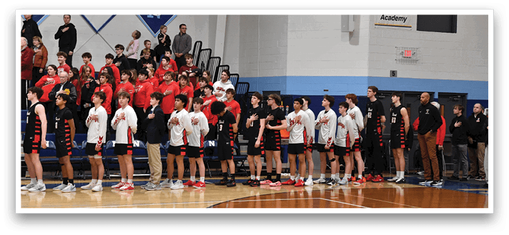 A group of people are standing on a basketball court, some wearing red shirts and others wearing black. They are lined up in front of a crowd of spectators. AI generated content
