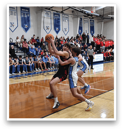 A basketball game is taking place with players on the court. One player is attempting to block a shot, while another player is trying to get past him. The crowd watches intently as the players compete. AI generated content