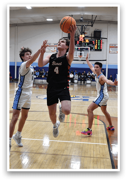 A group of young men playing basketball on a court. One player is attempting to block a shot, while others are running and jumping to gain possession of the ball. AI generated content