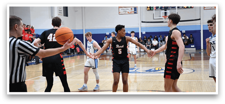 A group of young men are playing basketball on a court. One player is holding a basketball while others are shaking hands with each other. The referee is present to oversee the game. AI generated content
