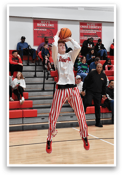 A man in a white shirt and red and white striped pants is jumping up to catch a basketball. AI generated content