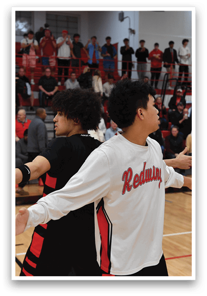 Two men wearing black and white shirts are on a basketball court, with one man holding the other's shoulders. They are surrounded by a crowd of people watching the game. AI generated content