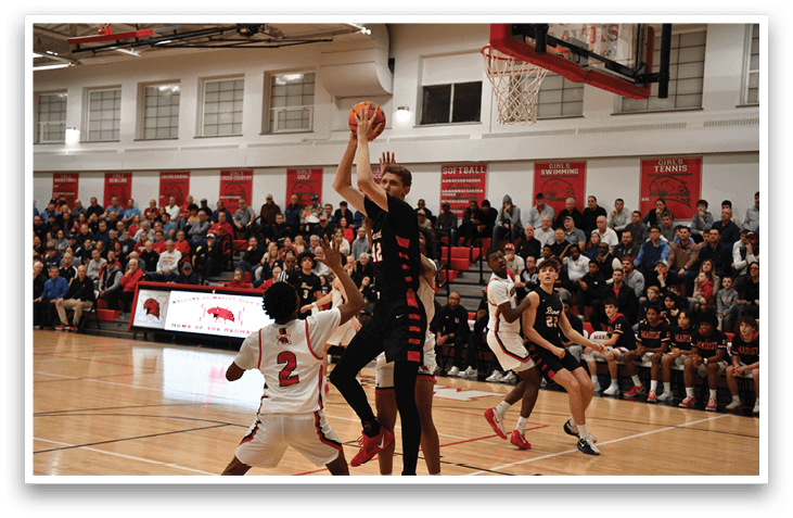 A basketball player is jumping to block a shot, while a crowd of people watches the game. AI generated content