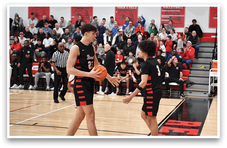 Two young men are playing basketball on a court, with one holding a basketball. They are surrounded by a crowd of people watching the game. AI generated content