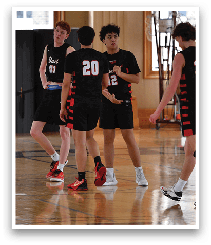 Four young men are playing basketball in a gym. AI generated content