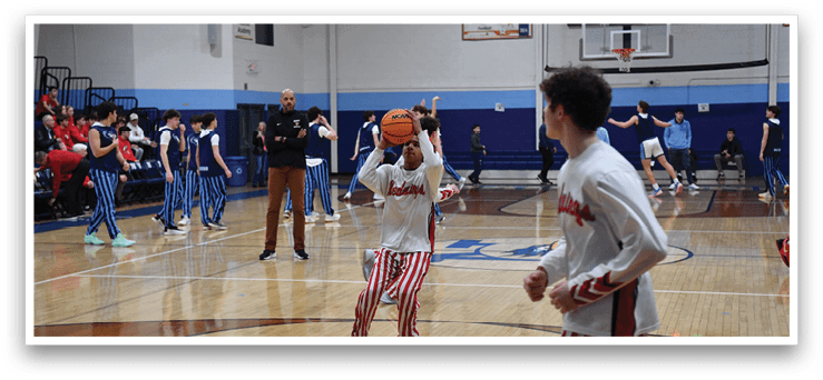 A basketball game is taking place with a group of men on the court. One man is holding a basketball, while another man is holding a basketball hoop. There are several other men on the court, some of them wearing striped pants. The scene is lively and full of action. AI generated content