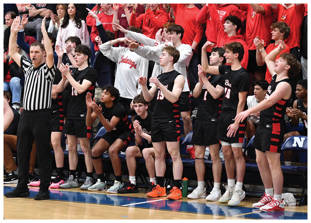 A group of people in a gym, some are wearing red shirts and others are wearing black. A referee is present, and a basketball is visible in the scene. AI generated content