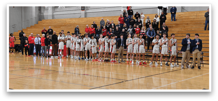 A group of people are standing on a basketball court, some of them wearing red and white uniforms. They are holding their hands up in the air, possibly in a cheer or celebration. The crowd is watching the event, and there are several benches in the background. AI generated content
