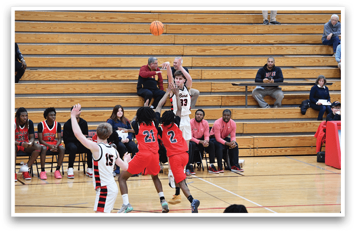 A group of people are playing basketball on a court. A man is jumping to shoot the ball. There are several other people watching the game. AI generated content