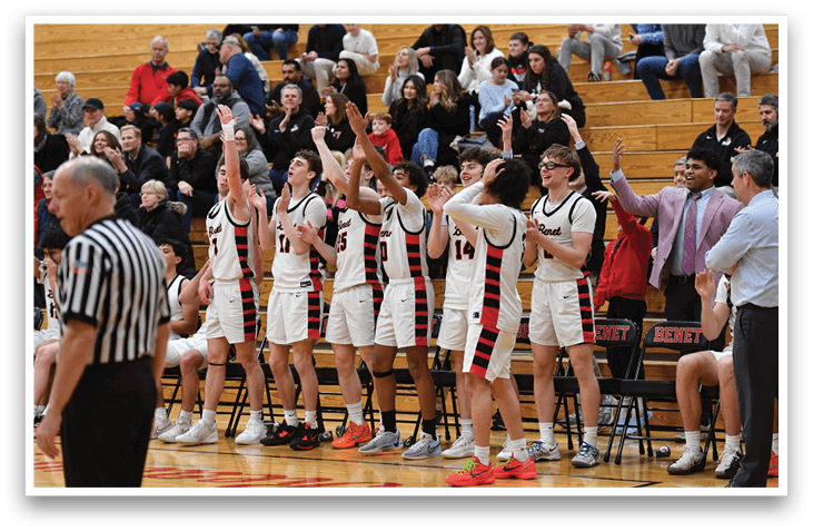 A group of young men are standing on a basketball court, wearing uniforms and holding their hands up. They are likely celebrating a victory or preparing for a game. The crowd of people in the stands are watching the event, showing their support and excitement. AI generated content