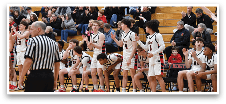 A group of young men are sitting on chairs in a gym, watching a basketball game. AI generated content