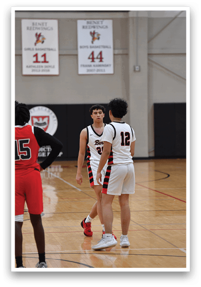 Two basketball players are walking on the court, one wearing a red jersey and the other wearing a white jersey. AI generated content