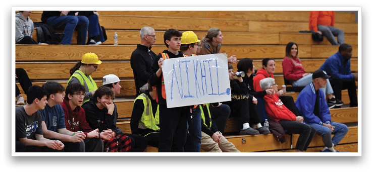 A group of people are sitting in the bleachers, watching a game. One man is holding a sign that says “activate." AI generated content
