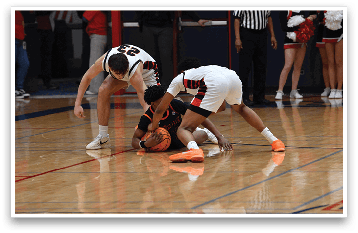 Two basketball players are on the floor, one with a ball in his hand. AI generated content