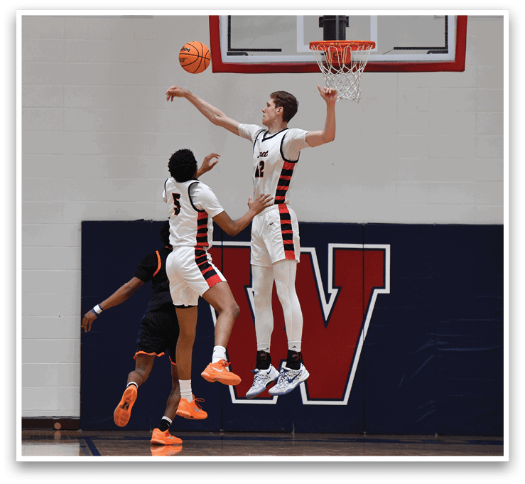 A basketball player leaps into the air to block a shot, while other players look on. AI generated content
