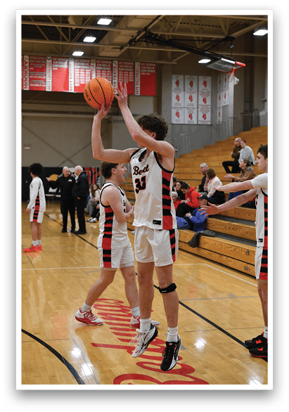 A group of basketball players are on a court, with one player jumping up to shoot a basketball. There are several other players on the court, some of them sitting on a bench. The scene is set in a gymnasium. AI generated content