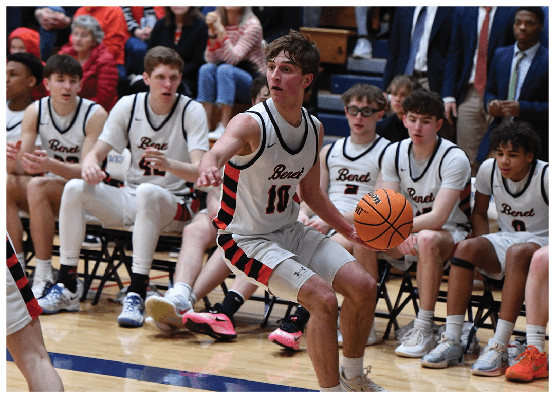 A group of basketball players are sitting on the floor of a gym, with some of them holding their basketballs. The players are wearing uniforms and are likely taking a break during a game. The crowd of spectators is watching the players from the stands. AI generated content