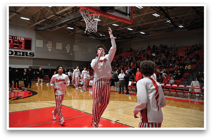 A basketball player in a white shirt and red and white striped pants is reaching up to shoot a basket. AI generated content