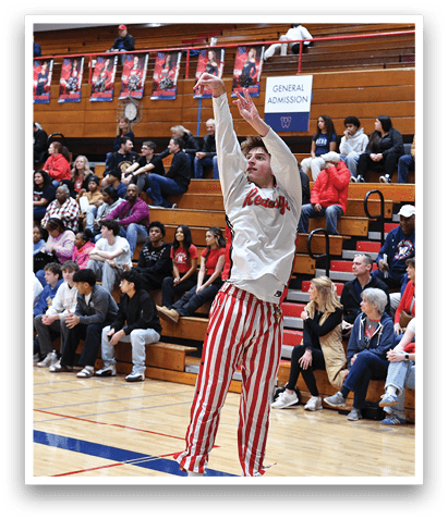 A man in a white shirt and red and white striped pants is jumping in the air to catch a basketball. AI generated content