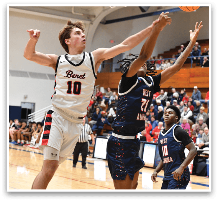 A basketball game is in progress with players on the court. One player is attempting to block a shot, while another player is reaching for the basketball. The crowd watches intently as the players compete. AI generated content