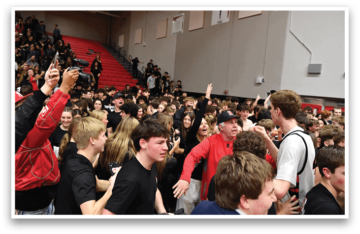 A group of people are gathered in a gymnasium, with some of them holding cell phones. The crowd is diverse, with individuals of various ages and genders. The gymnasium is filled with excitement, as the people are celebrating a victory. AI generated content
