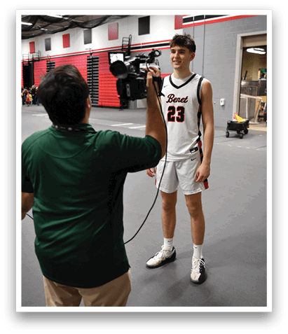 A man in a green shirt is holding a microphone and interviewing a man in a basketball uniform. AI generated content