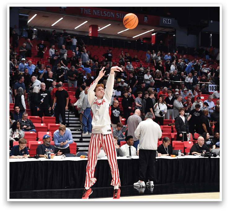 A man in a white shirt and red and white striped pants is jumping to catch a basketball. AI generated content