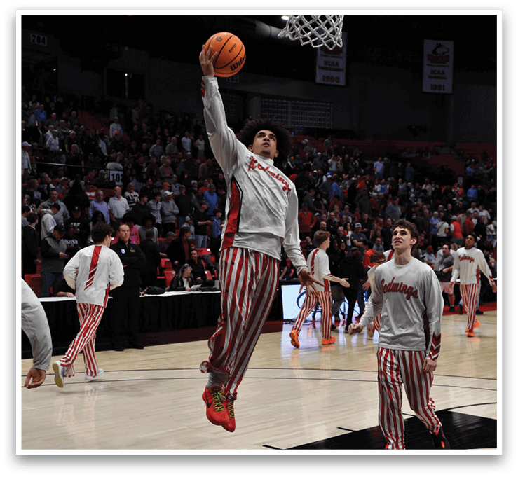 Three men wearing striped pants are playing basketball. One of them is jumping in the air to grab the basketball. AI generated content
