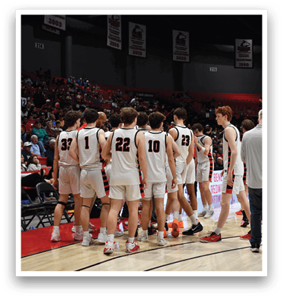 A group of basketball players huddle on the court, with one man in a gray shirt and blue jeans standing among them. AI generated content