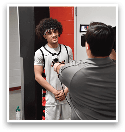 A man wearing a white shirt and black shorts stands next to a man wearing a gray shirt. Both men are holding microphones. AI generated content