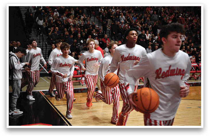 A group of young men wearing red and white striped pants are running on a basketball court. They are holding basketballs and appear to be playing a game. AI generated content