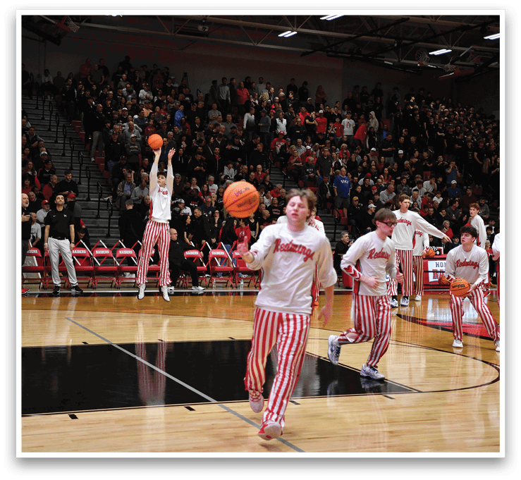 A group of basketball players are on the court, with one player holding a basketball in the air. The players are wearing red and white striped pants. AI generated content