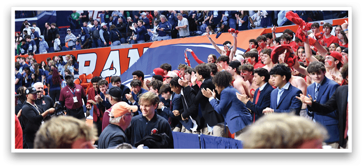 A group of people are in a stadium, some of them are holding up red and blue items. The crowd is cheering and clapping, and there are several people wearing ties. The event appears to be a sports game, as the spectators are gathered to watch the game. AI generated content