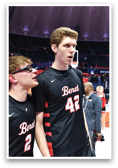 A group of men in black shirts and shorts stand on a basketball court. One of the men is wearing glasses and appears to be looking at the camera. AI generated content
