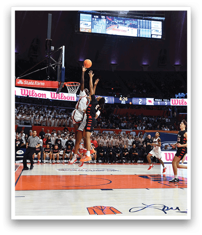 A basketball game is in progress with a player jumping to block a shot. AI generated content