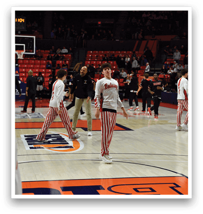 A group of men wearing red and white striped pants are playing basketball on a court. AI generated content