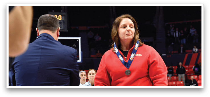 A woman wearing a red shirt and a medal stands on a basketball court. AI generated content
