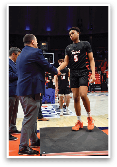 A group of men are standing on a basketball court, engaged in conversation. One man is wearing a black shirt with the number 5 on it. AI generated content
