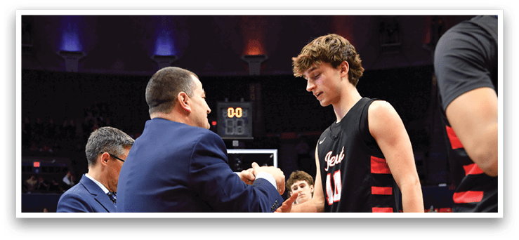 A group of men are standing on a basketball court, engaged in conversation. One man is holding a cell phone, possibly showing something to the others. The men are wearing sports uniforms, indicating that they are likely basketball players. AI generated content